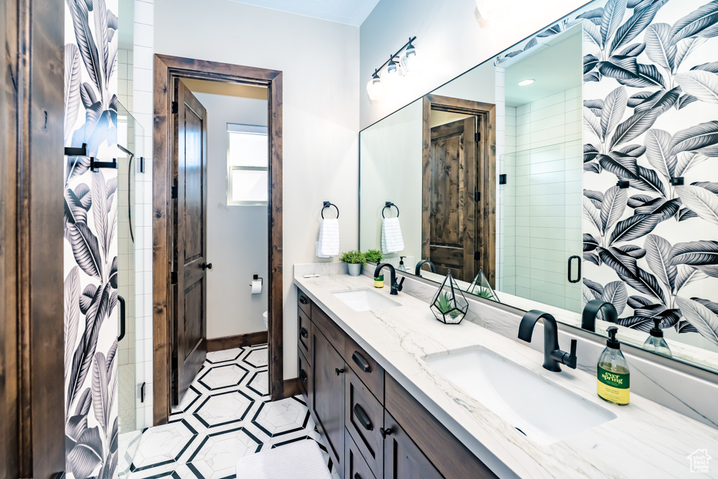 Full bathroom featuring a sink, double vanity, baseboards, and a shower stall