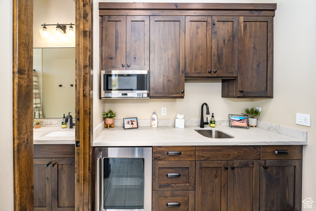 Kitchen with wine cooler, a sink, and dark brown cabinetry
