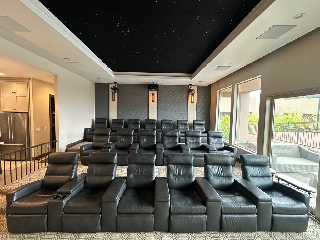 Home theater room featuring a raised ceiling and wallpapered walls