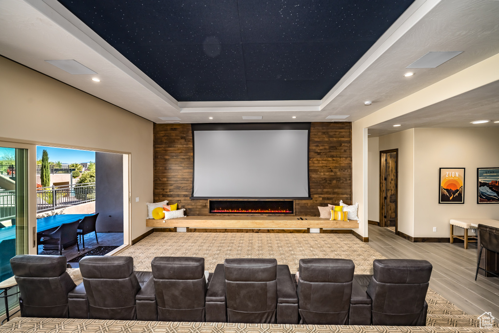 Home theater with wood finished floors, baseboards, a raised ceiling, and recessed lighting