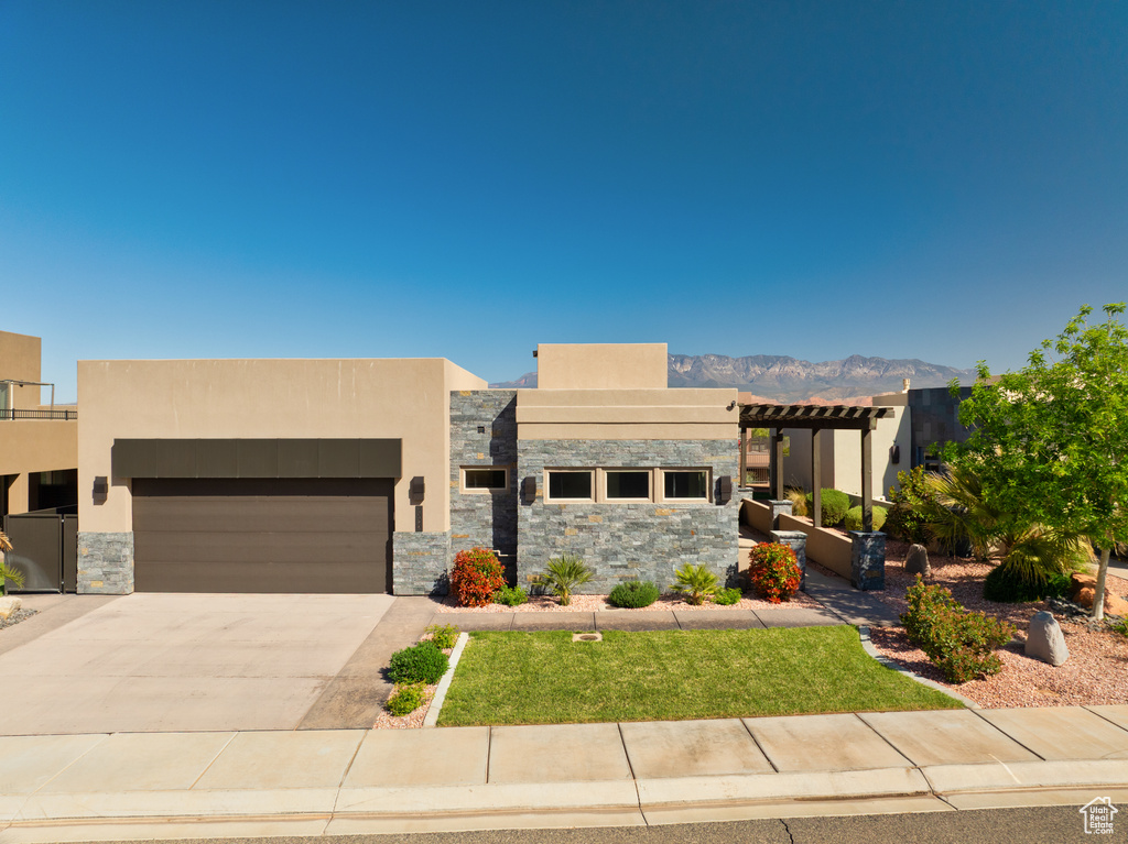 Contemporary home featuring an attached garage, stucco siding, and stone siding