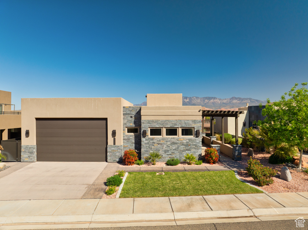Contemporary home featuring an attached garage, stucco siding, stone siding, and driveway