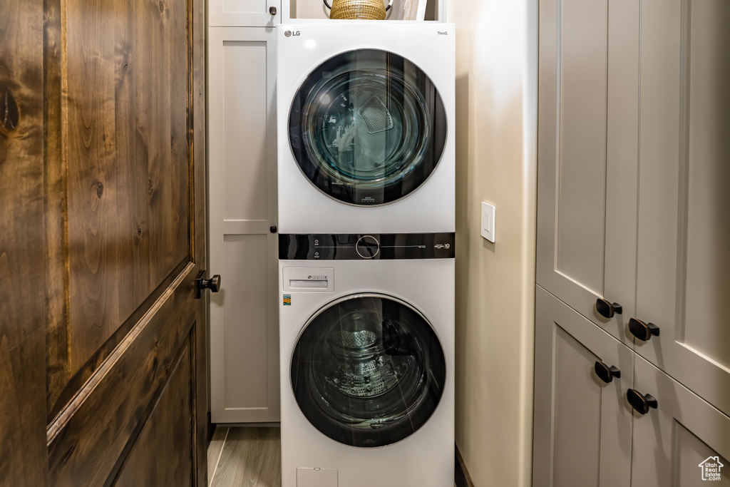 Laundry room featuring cabinet space, stacked washer and dryer, and wood finished floors