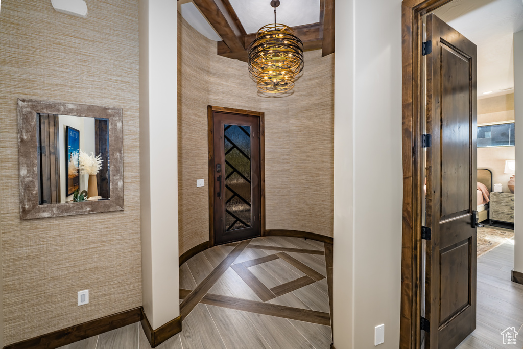 Interior space featuring baseboards, beamed ceiling, and a notable chandelier
