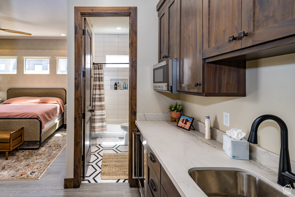Interior space featuring stainless steel microwave, a sink, and dark brown cabinetry
