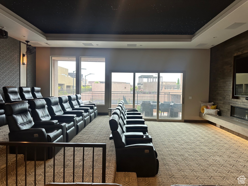 Carpeted home theater featuring baseboards, a wealth of natural light, a tray ceiling, and a large fireplace