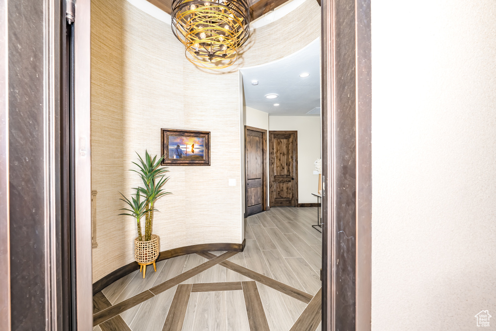 Hallway with baseboards, a notable chandelier, and recessed lighting