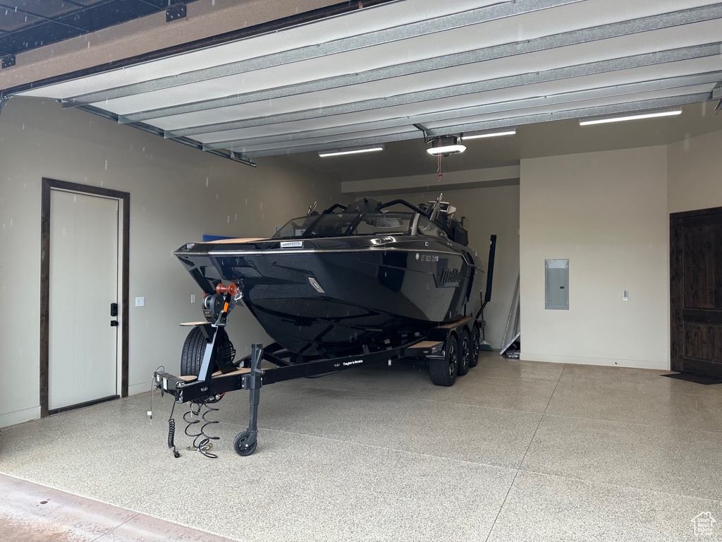 Garage with electric panel, baseboards, and a garage door opener