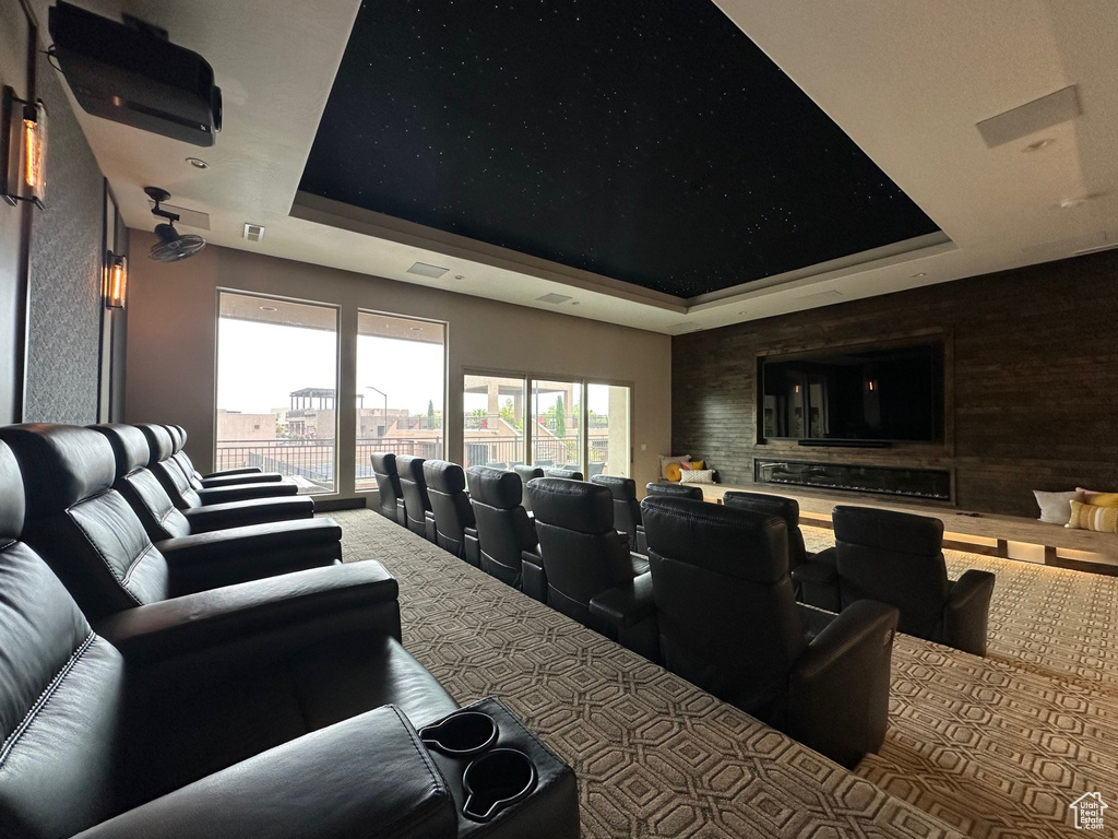 Carpeted home theater room with a tray ceiling and visible vents