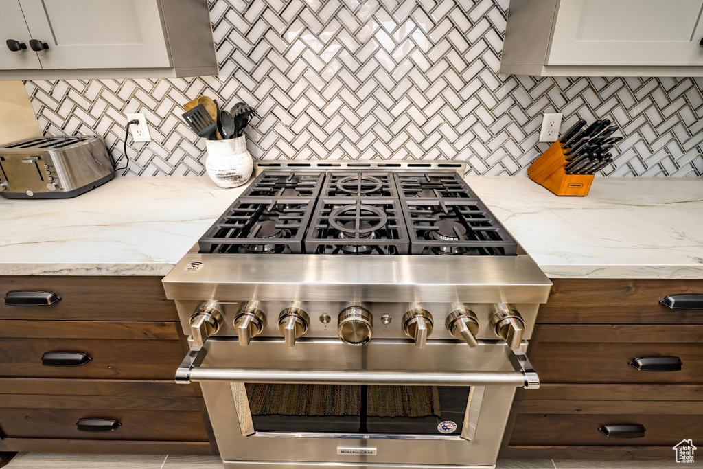 Kitchen featuring a toaster, decorative backsplash, light stone countertops, and high end range