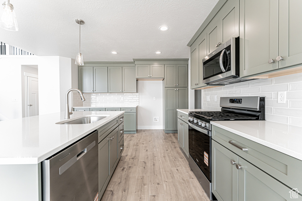 Kitchen featuring appliances with stainless steel finishes, gray cabinetry, light countertops, recessed lighting, and light wood finished floors