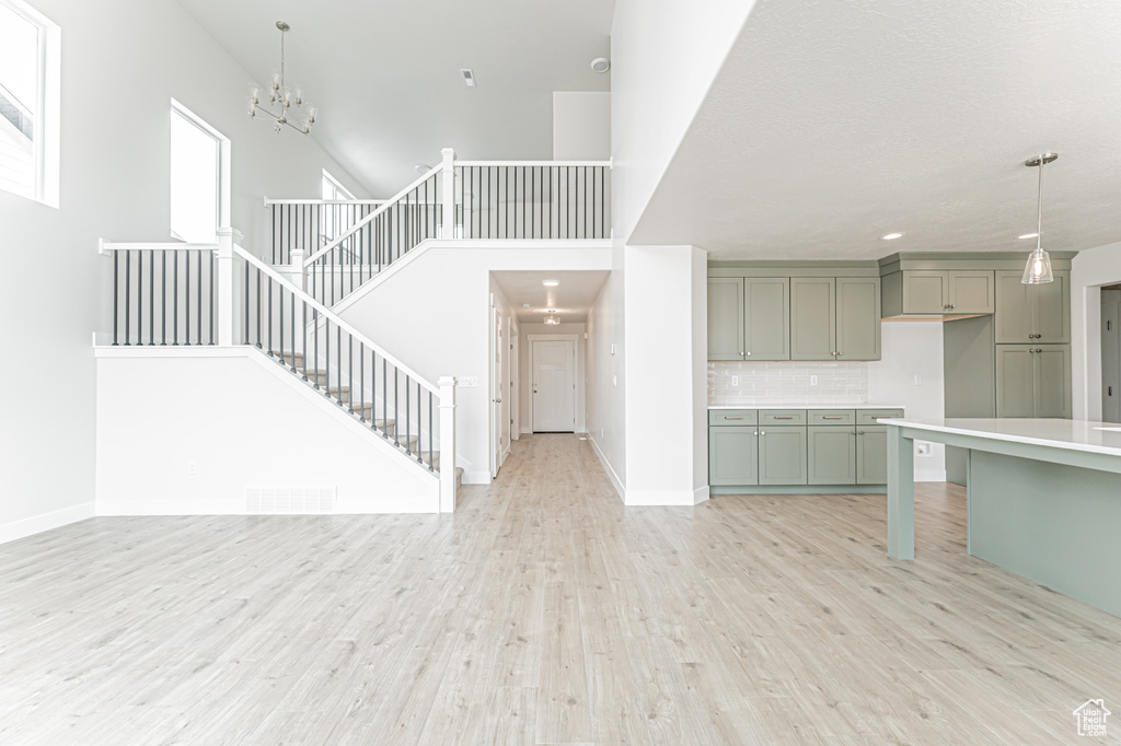 Unfurnished living room with light wood finished floors, a chandelier, stairs, and recessed lighting