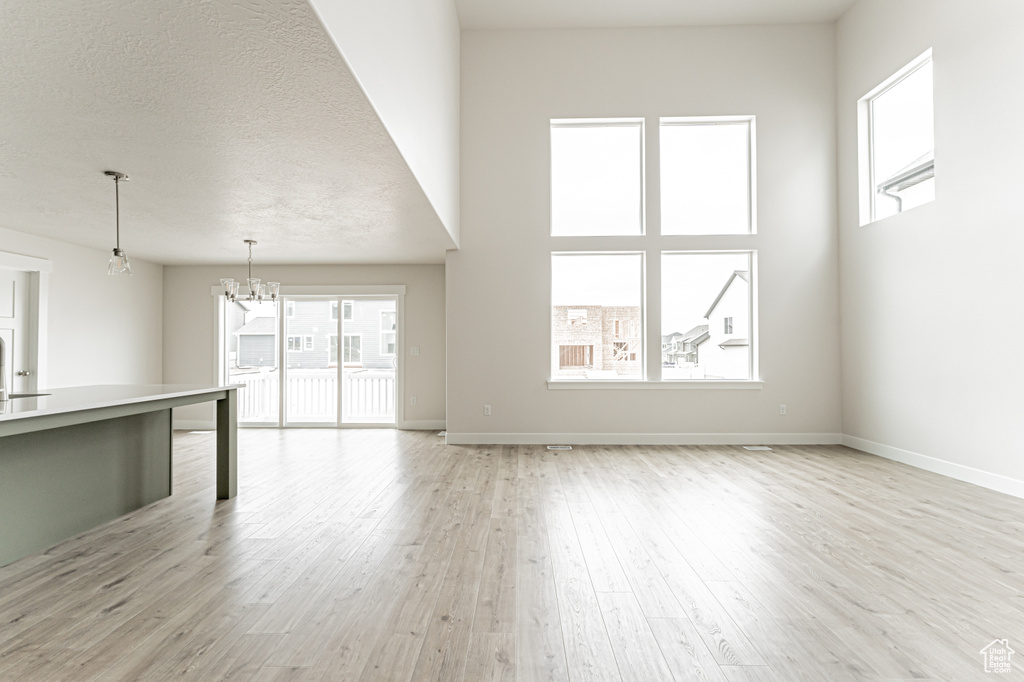 Unfurnished living room with light wood-style floors and a chandelier