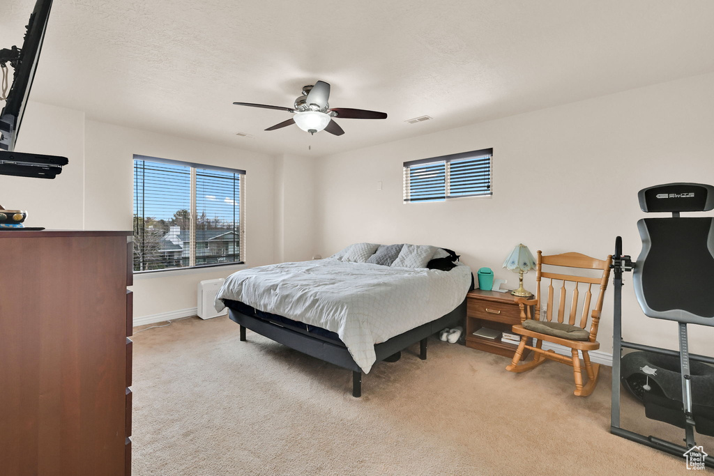 Bedroom with a ceiling fan, light carpet, baseboards, and visible vents