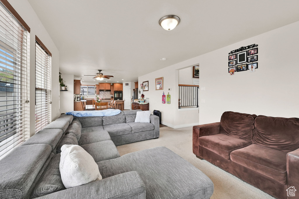 Living room featuring light carpet, baseboards, and a ceiling fan