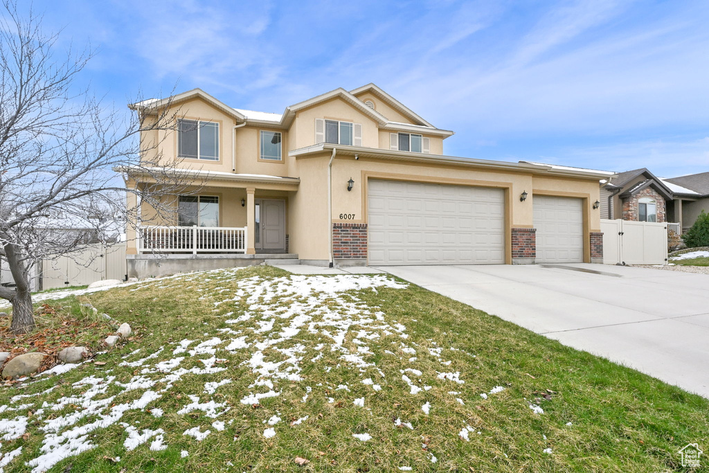 View of front of property featuring driveway, fence, a garage, stucco siding, and a porch
