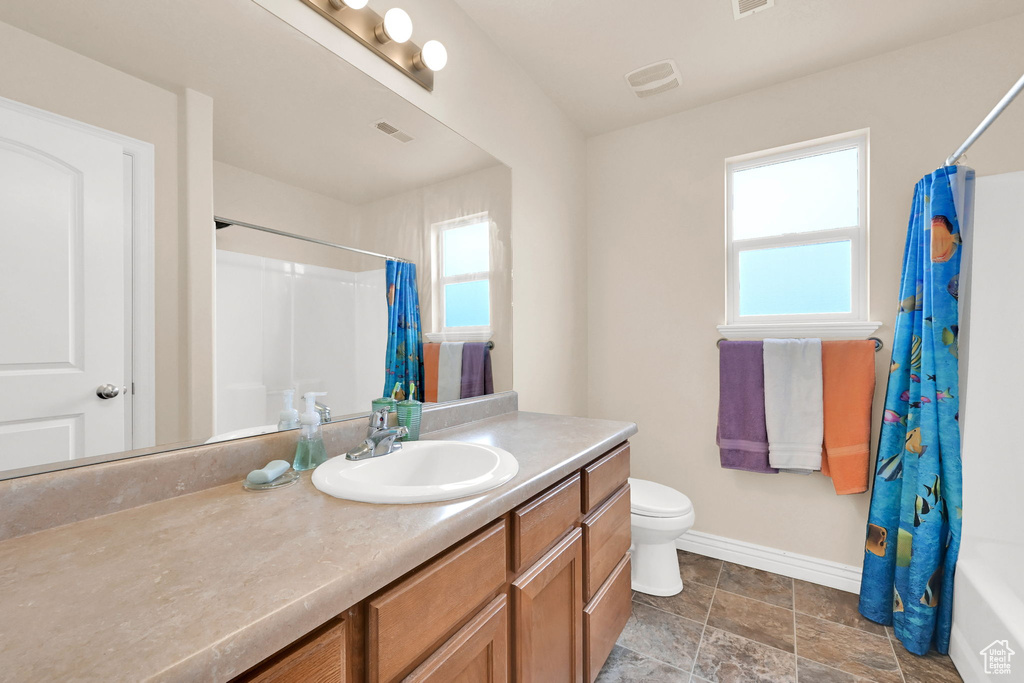 Full bath with toilet, vanity, baseboards, and visible vents