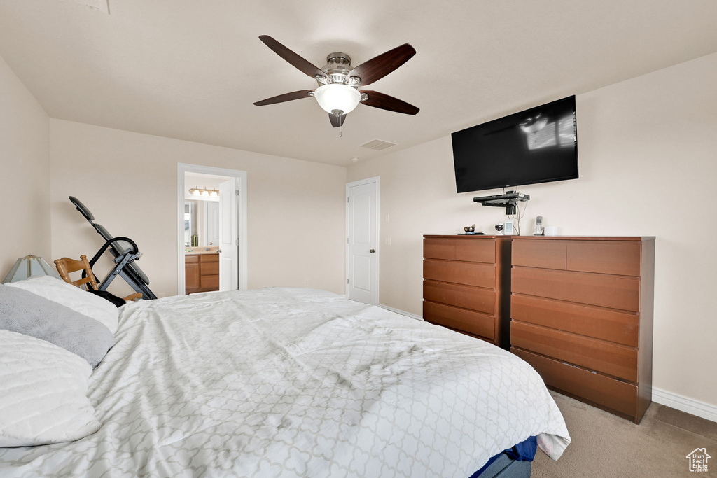 Bedroom featuring ensuite bathroom, visible vents, baseboards, a ceiling fan, and light carpet
