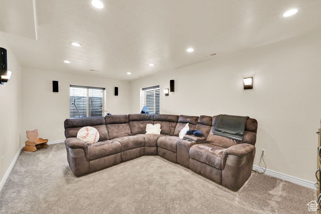 Carpeted living room featuring baseboards, visible vents, recessed lighting, and a textured ceiling