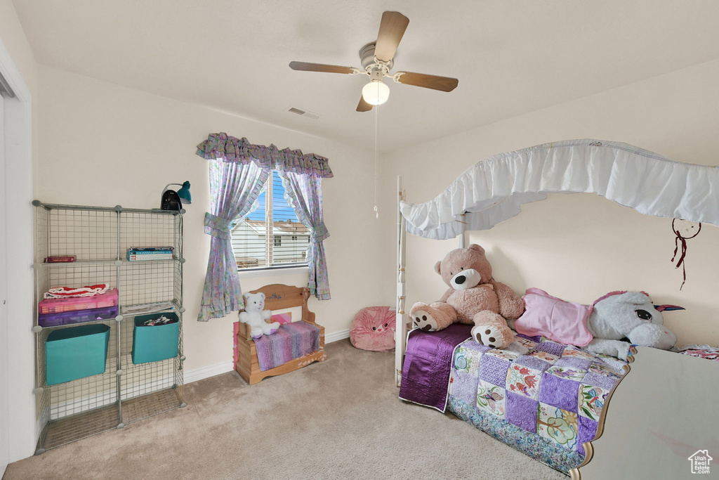 Carpeted bedroom with baseboards, visible vents, and a ceiling fan