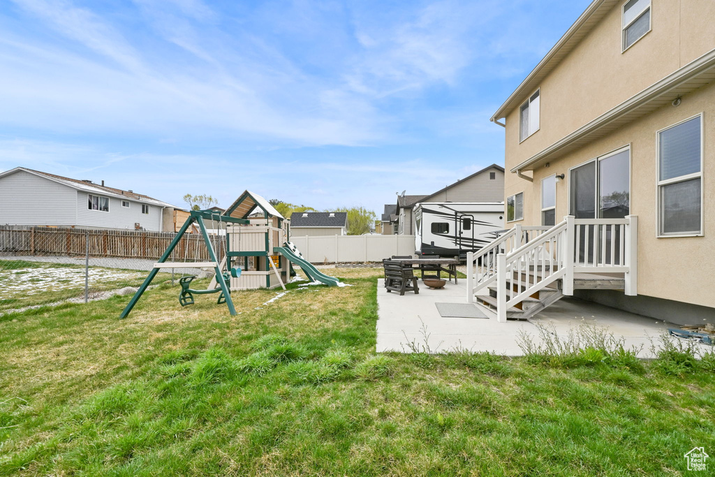View of yard featuring a fenced backyard, a playground, and a patio area