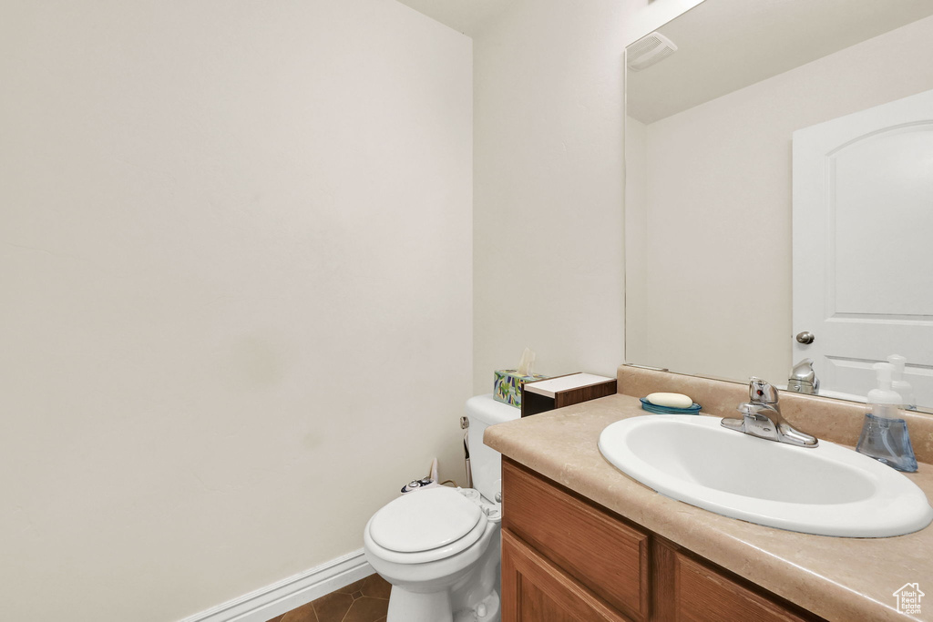 Bathroom featuring baseboards, toilet, tile patterned flooring, and vanity