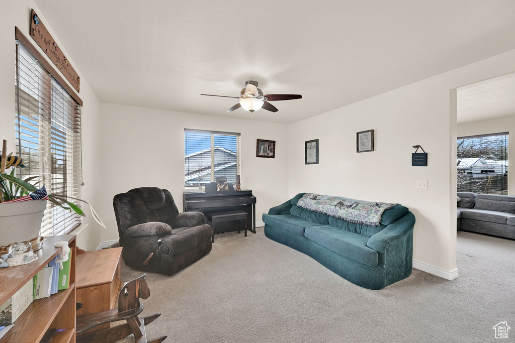 Living room with baseboards, carpet flooring, and a ceiling fan