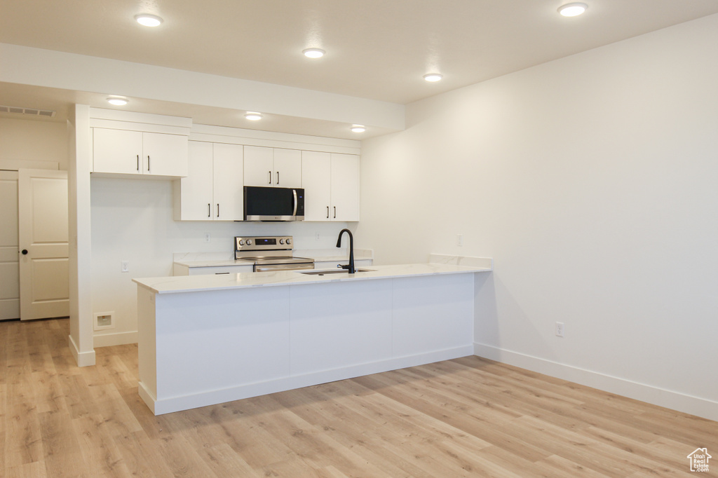 Kitchen featuring light countertops, stainless steel appliances, a sink, visible vents, and a peninsula