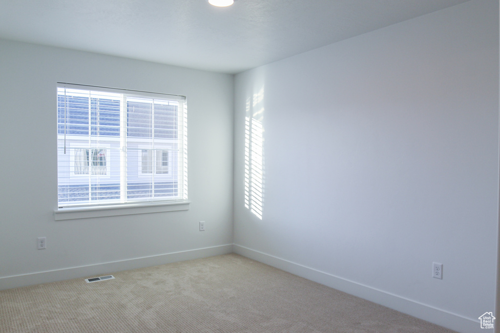 Empty room featuring light carpet, baseboards, and visible vents