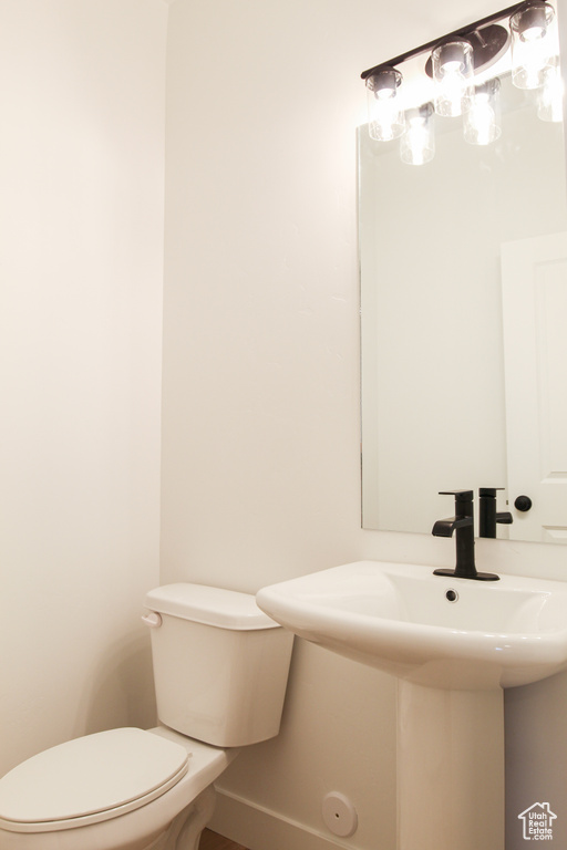 Half bath featuring baseboards, toilet, and a sink