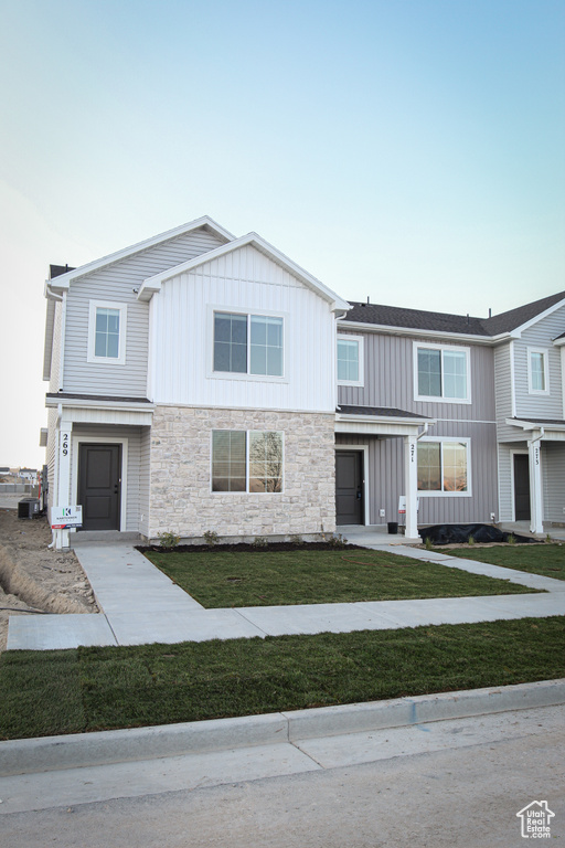 Townhome / multi-family property featuring stone siding, board and batten siding, and a front lawn
