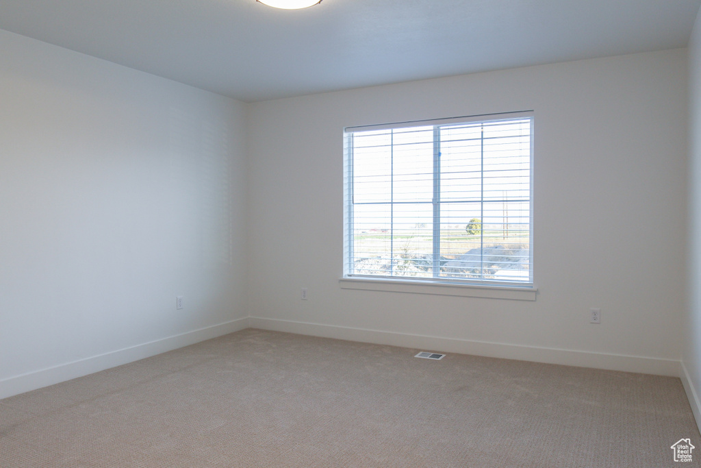Spare room featuring light carpet, baseboards, and visible vents
