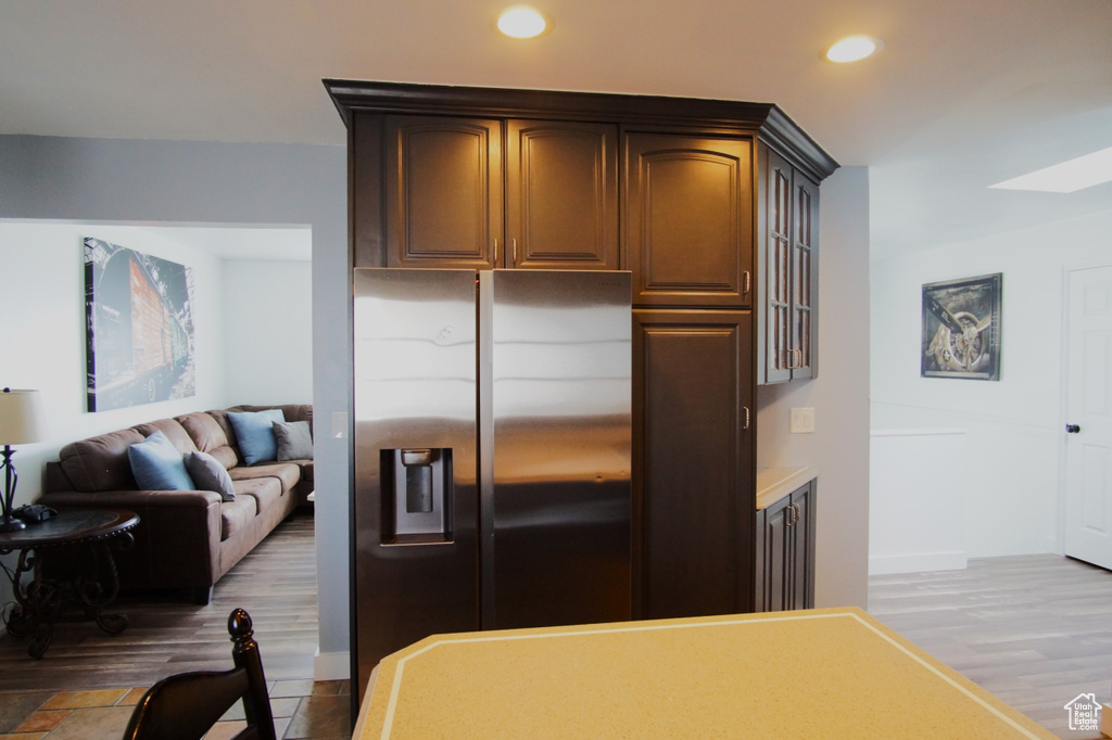Kitchen with stainless steel fridge, a skylight, wood finished floors, recessed lighting, and open floor plan