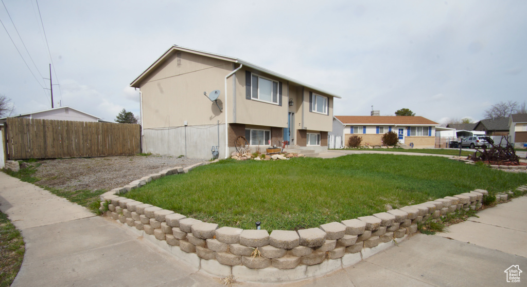 View of front of home with a front yard, fence, and stucco siding