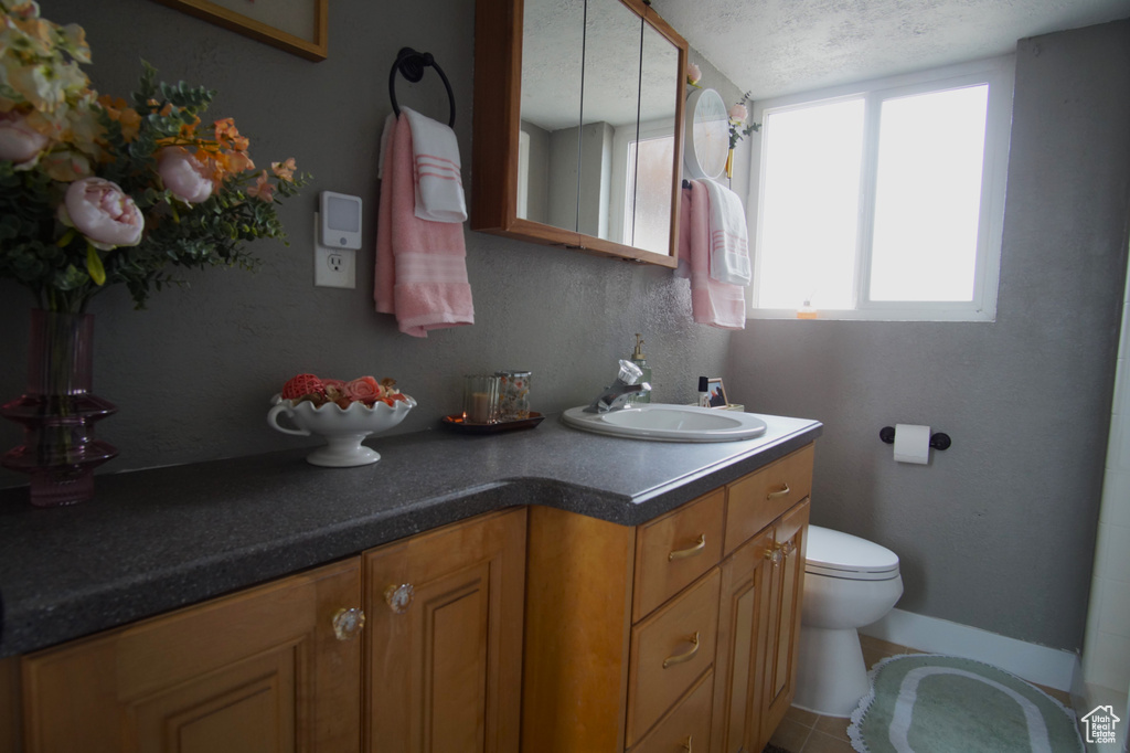 Bathroom featuring baseboards, toilet, vanity, and a textured ceiling