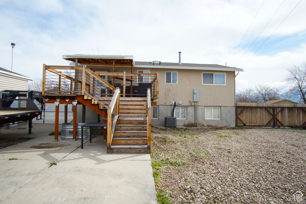 Rear view of property featuring cooling unit, a wooden deck, fence, and stairway