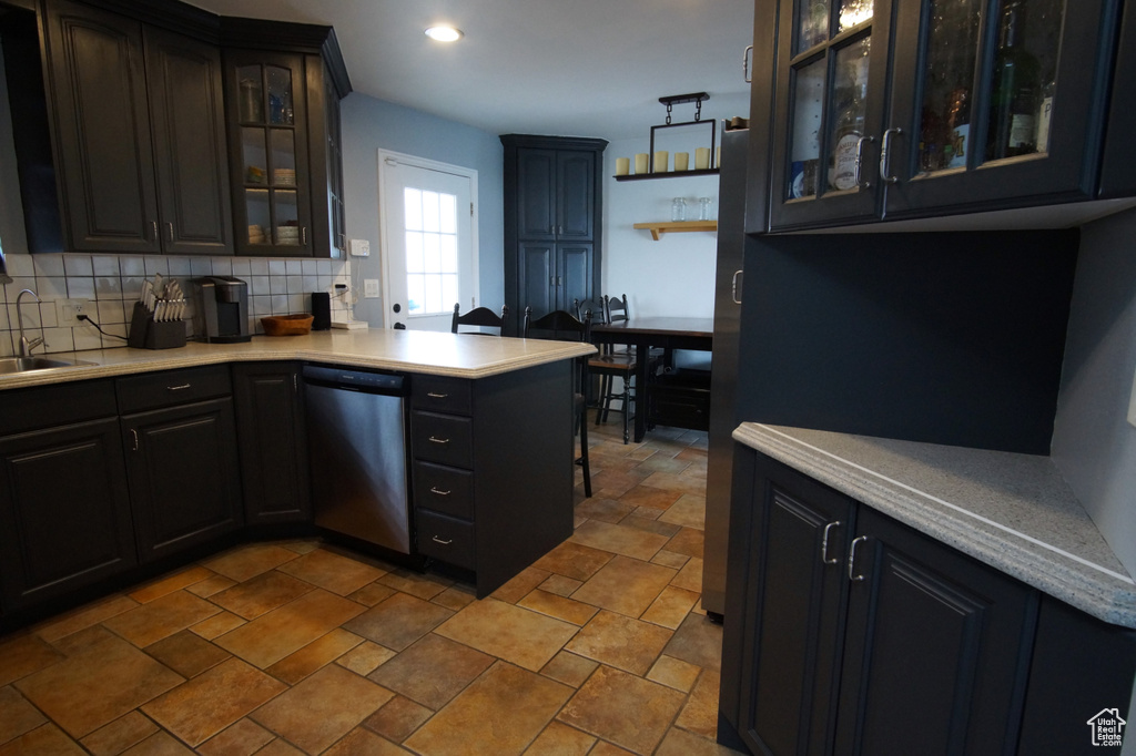 Kitchen with light countertops, a sink, tasteful backsplash, and dishwasher