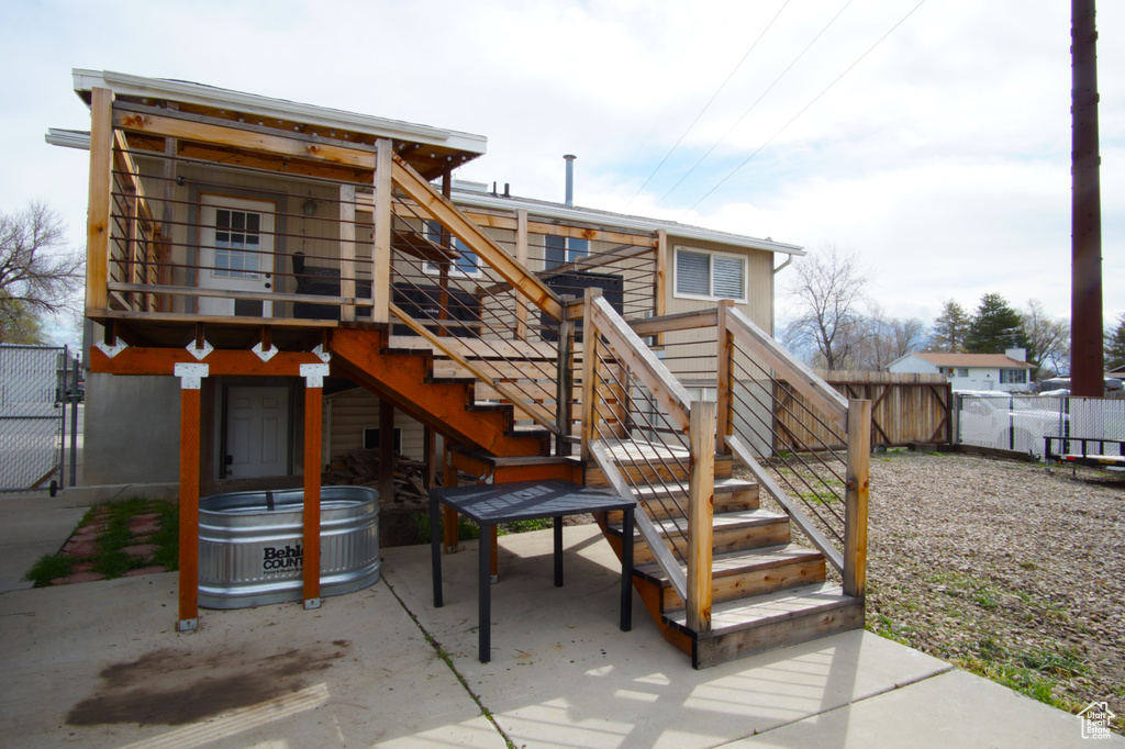 Back of house with a jacuzzi, fence, a patio, and stairway