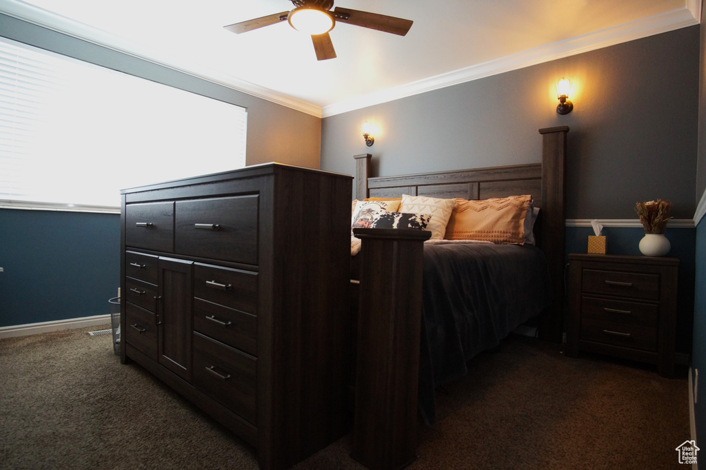 Bedroom featuring baseboards, a ceiling fan, dark carpet, and crown molding