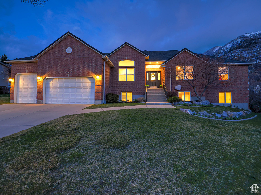 View of front of house with brick siding, a front yard, concrete driveway, and a garage