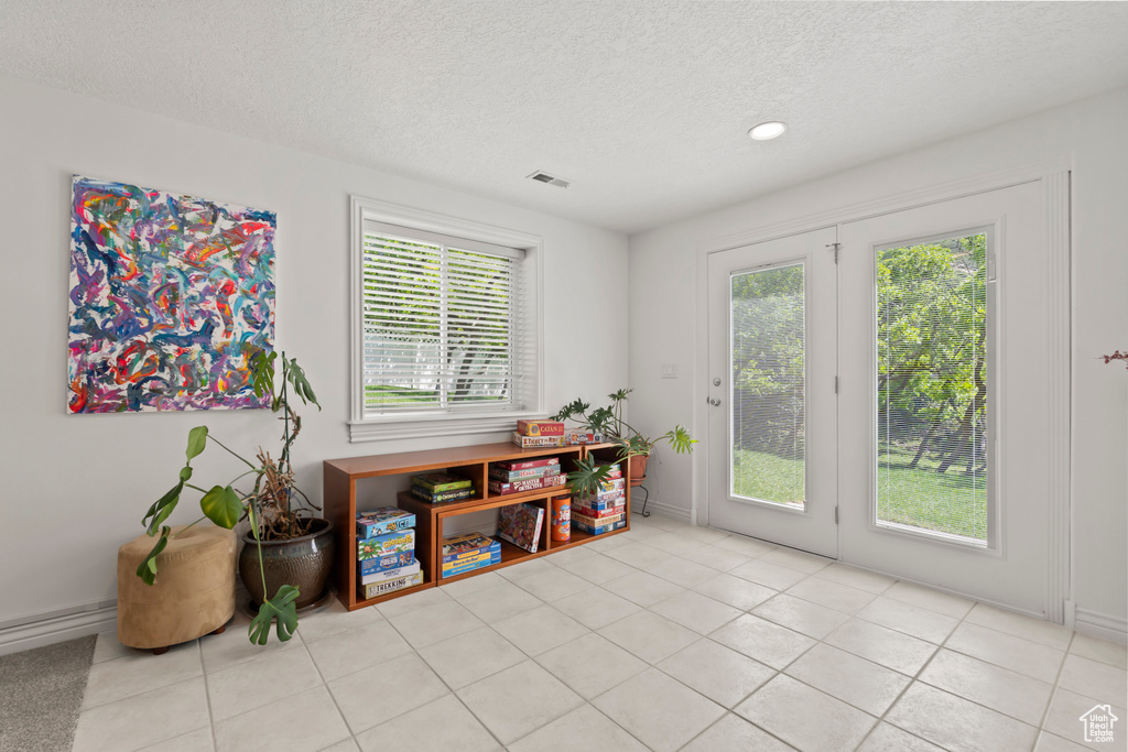 Dining space featuring a textured ceiling, light tile patterned floors, recessed lighting, and baseboards