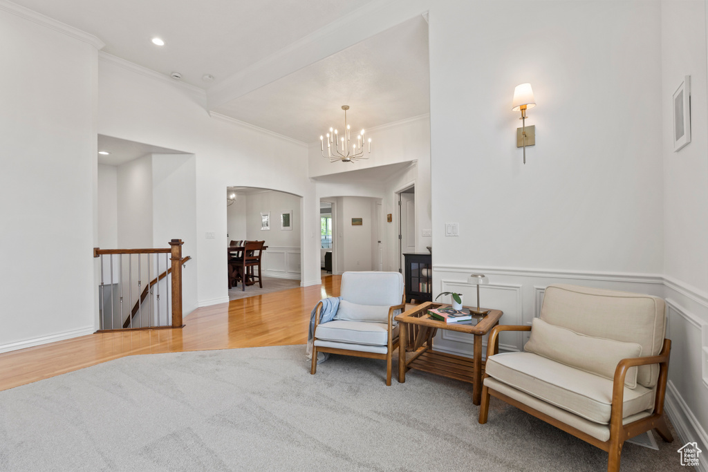 Sitting room with an upstairs landing, crown molding, arched walkways, a chandelier, and wood finished floors
