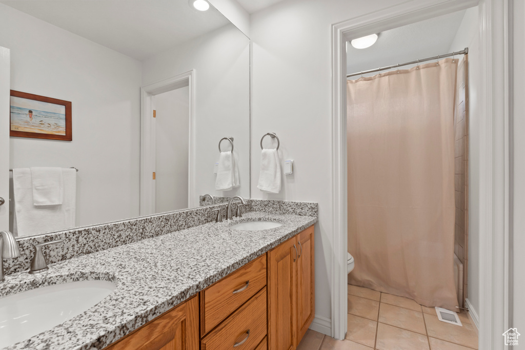 Bathroom with tile patterned flooring, double vanity, toilet, and a shower with curtain