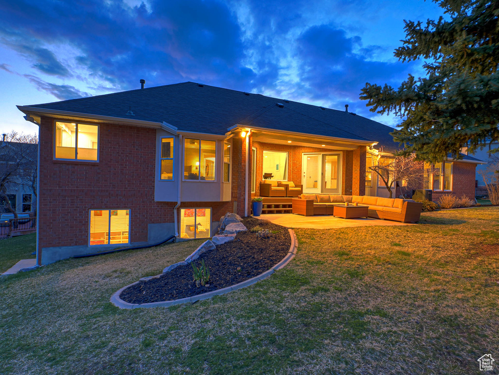 Back of house with outdoor lounge area, brick siding, a yard, roof with shingles, and a patio