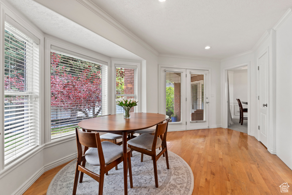 Dining room featuring healthy amount of natural light, crown molding, light wood-style flooring, baseboards, and recessed lighting