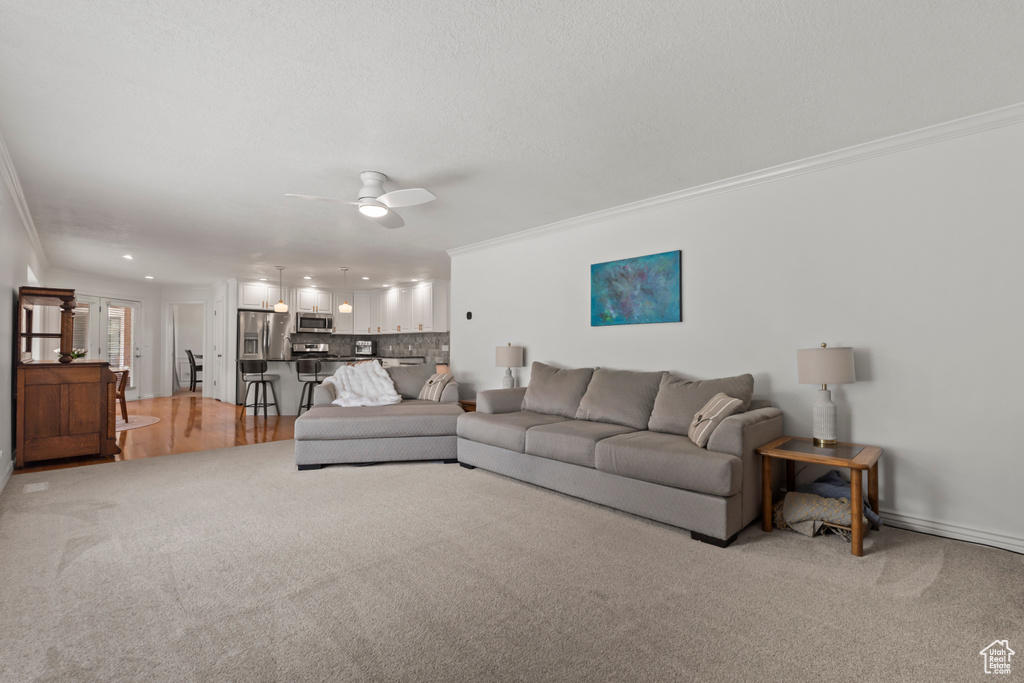 Living area featuring crown molding, light colored carpet, ceiling fan, baseboards, and recessed lighting