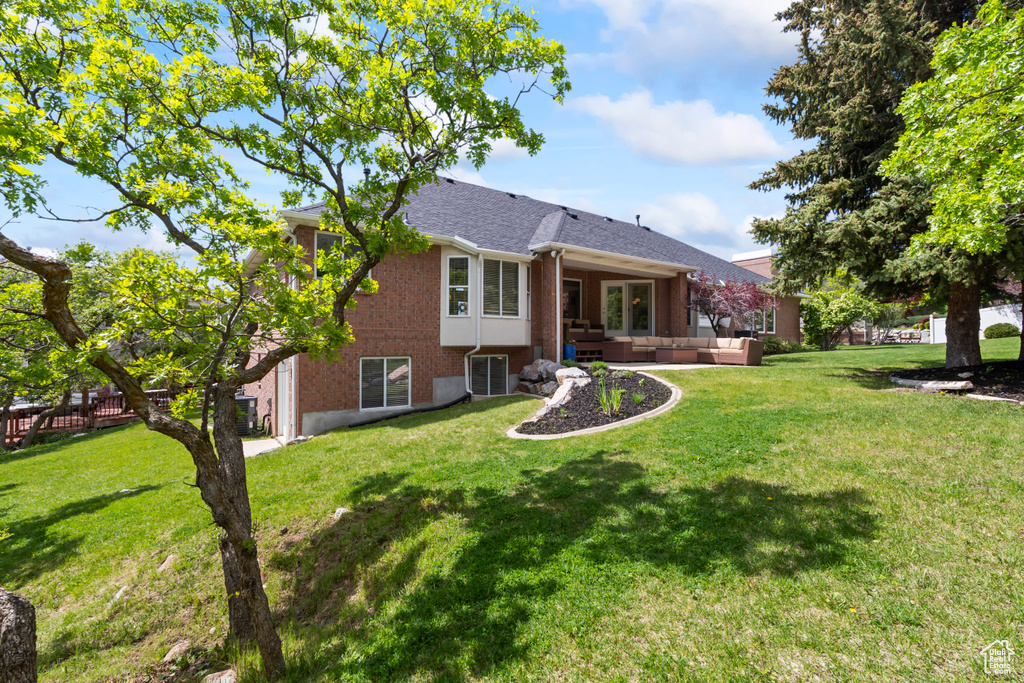 View of front facade featuring outdoor lounge area, brick siding, a front yard, and a shingled roof