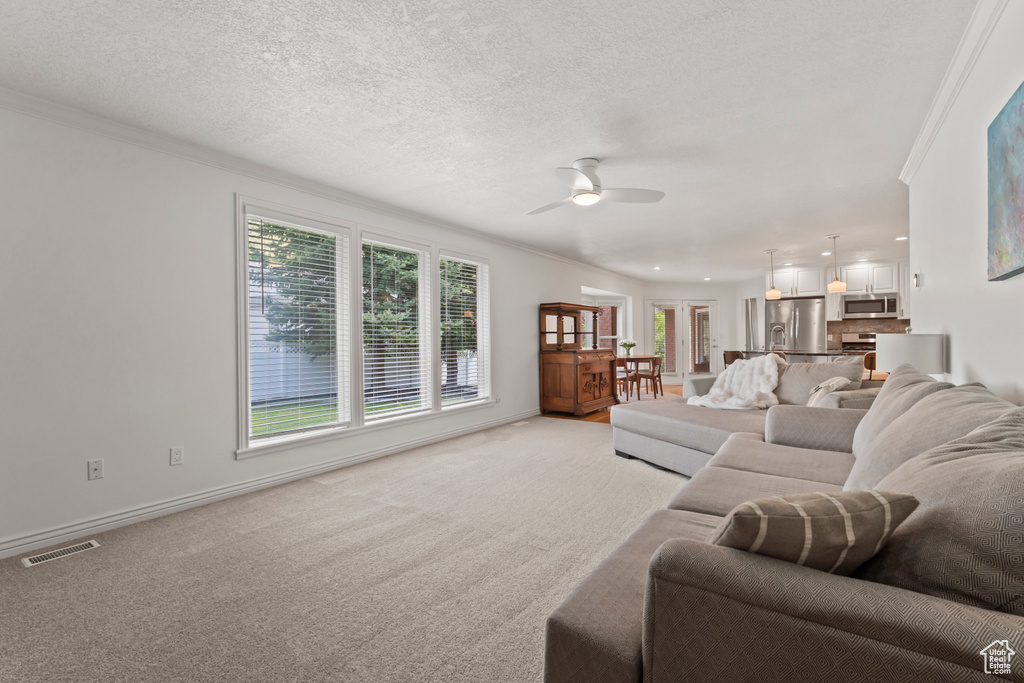 Living room featuring crown molding, ceiling fan, light carpet, baseboards, and recessed lighting