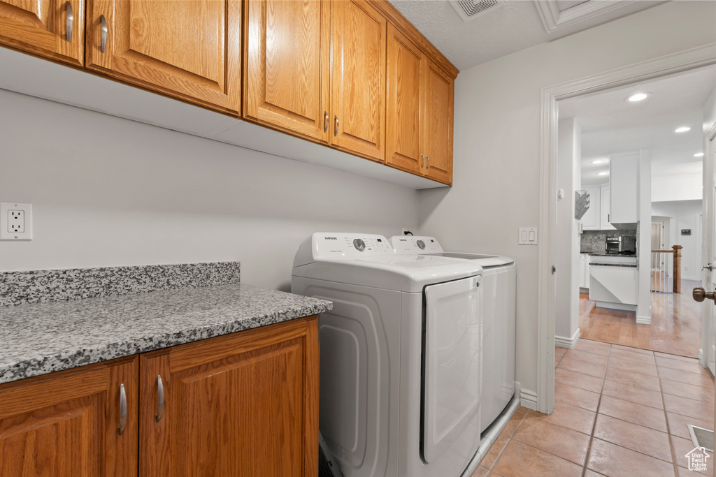 Laundry room with cabinet space, washer and clothes dryer, light tile patterned floors, and recessed lighting
