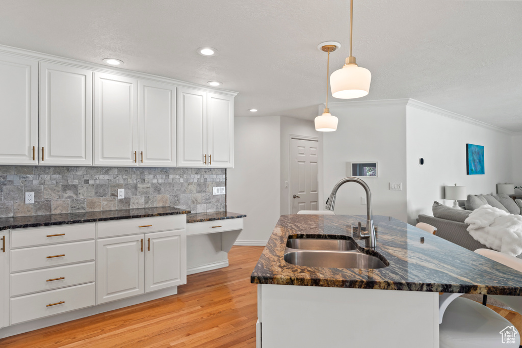 Kitchen with a sink, decorative backsplash, a breakfast bar, white cabinets, and crown molding